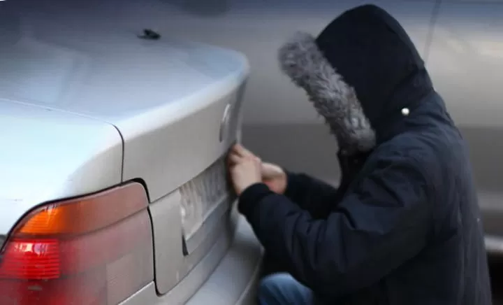 Злоумышленник скручивает номерные знаки у автомобиля